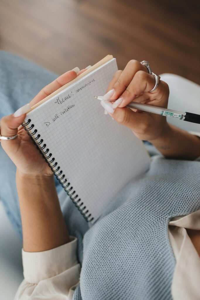 Person writing in a notebook with a pen, focusing on learning and education.